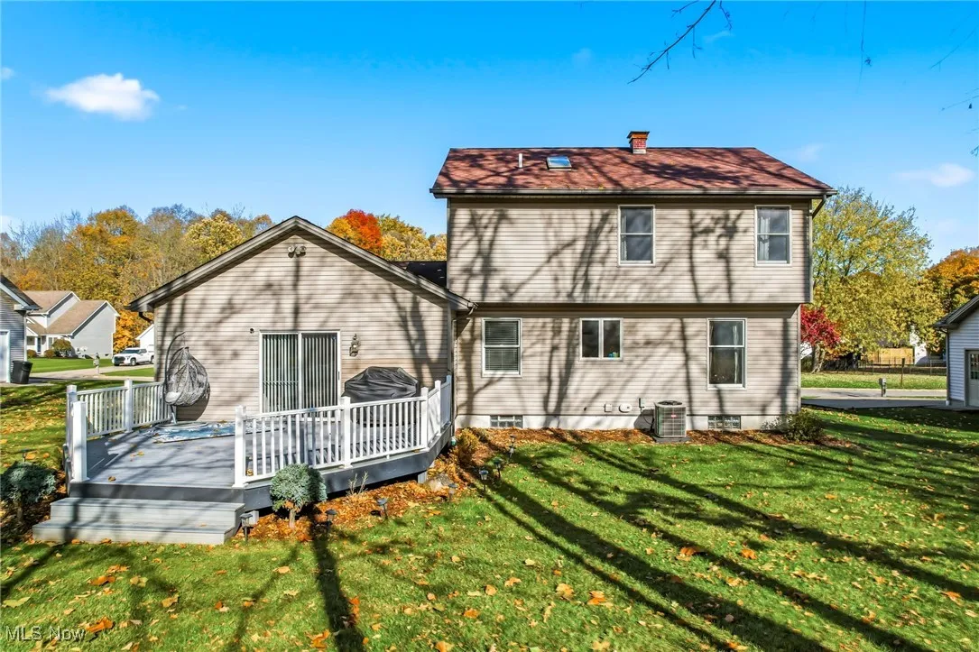 Rear view of house featuring a yard, a chimney, and a deck