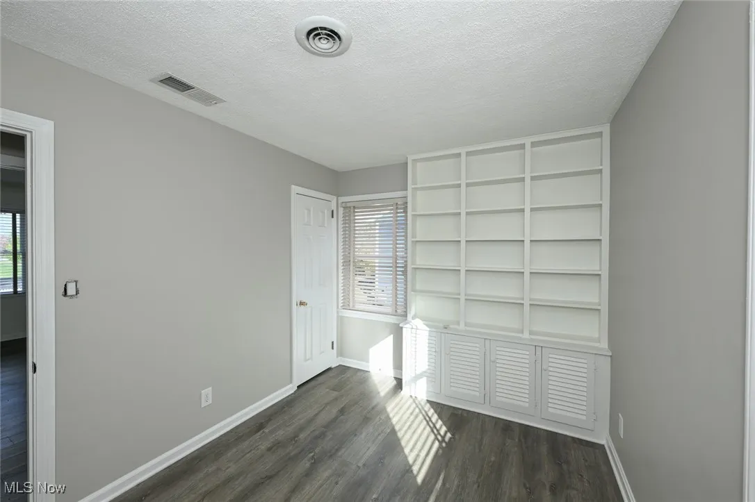 Unfurnished bedroom featuring a textured ceiling and dark wood-style floors