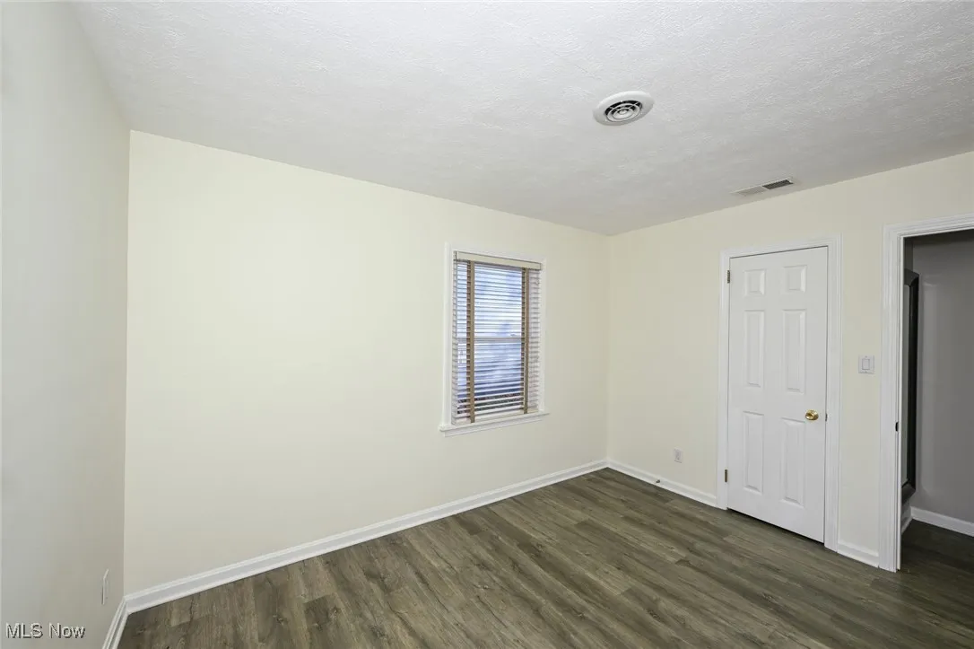 Unfurnished bedroom with dark wood-style flooring and a textured ceiling