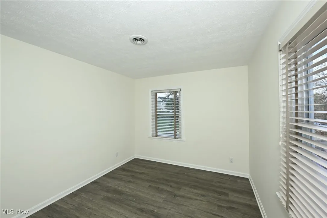 Unfurnished room featuring dark wood finished floors and a textured ceiling
