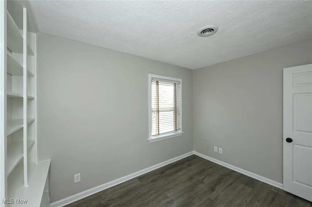 Unfurnished room with a textured ceiling and dark wood-style floors