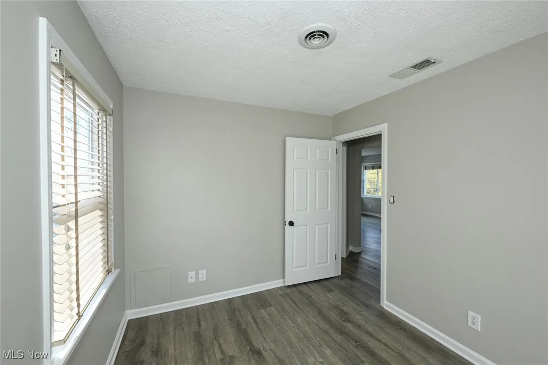 Unfurnished bedroom featuring a textured ceiling and dark wood-style floors