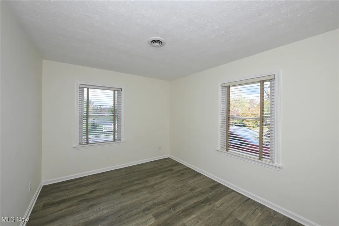 Spare room featuring dark wood-type flooring and a textured ceiling