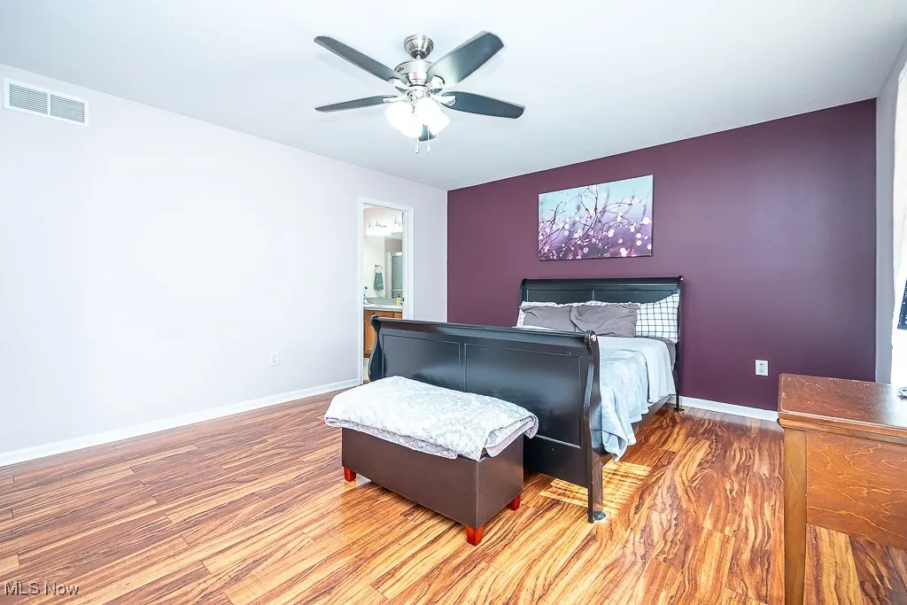 Bedroom featuring wood finished floors, ceiling fan, and connected bathroom