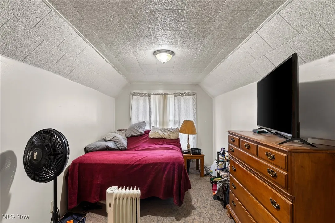 Bedroom with lofted ceiling and light colored carpet