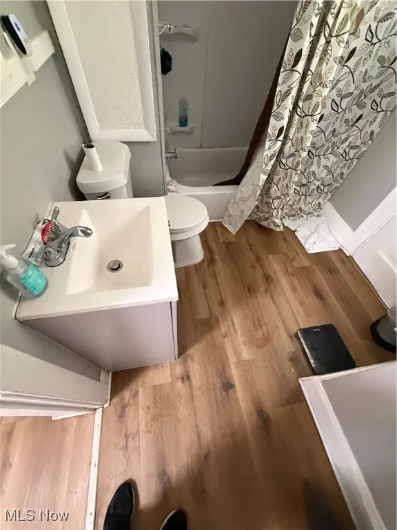 Full bath featuring vanity, shower / bath combination with curtain, and light wood finished floors