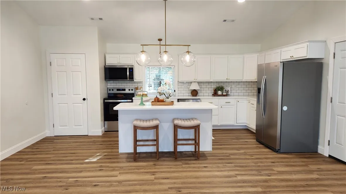 Kitchen with appliances, tile backsplash, solid surface counters, and USA-made cabinets