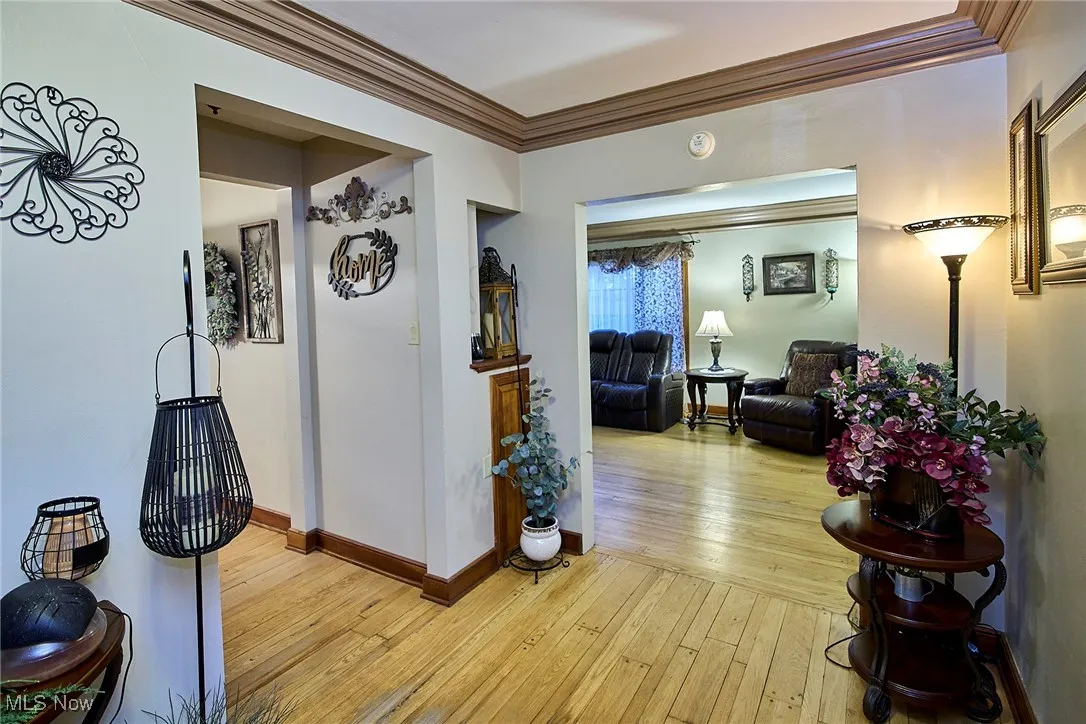 Corridor with ornamental molding and light wood-style floors