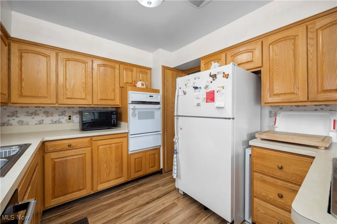 Kitchen featuring white appliances, light countertops, laminate flooring, oak cabinets