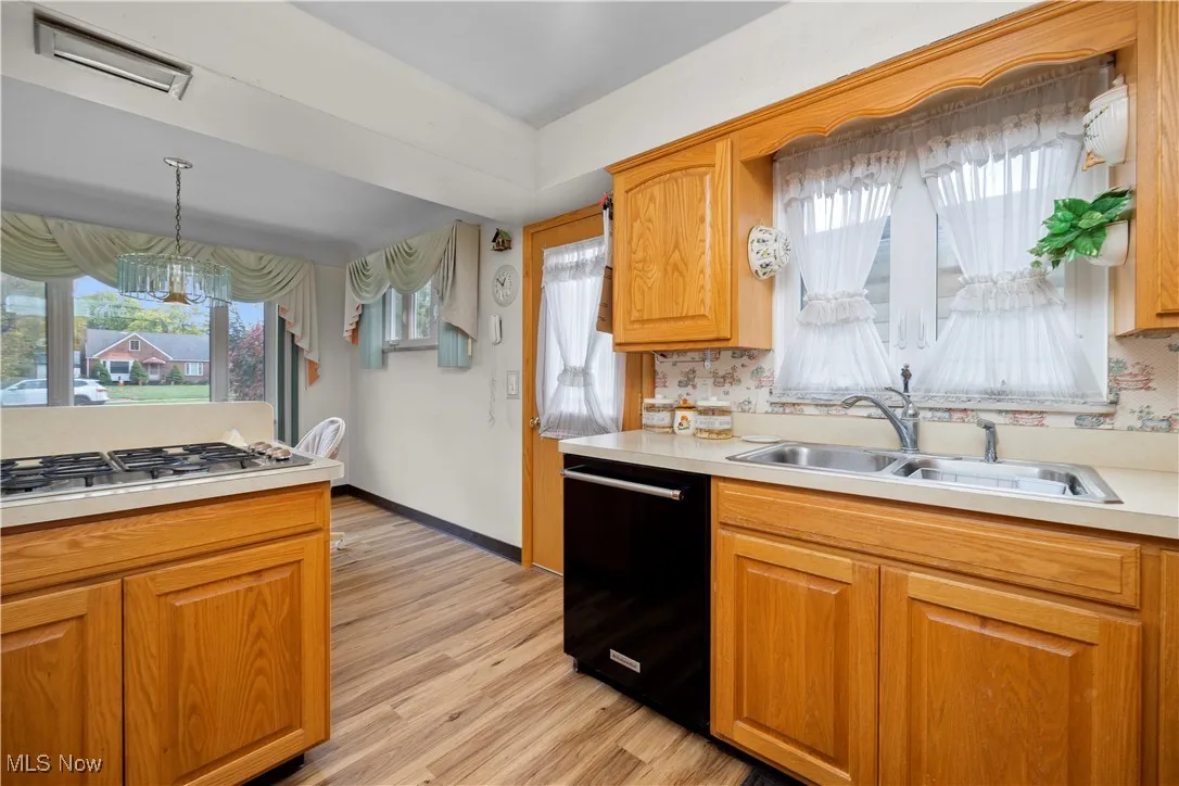 Kitchen featuring white appliances, light countertops, laminate flooring, oak cabinets