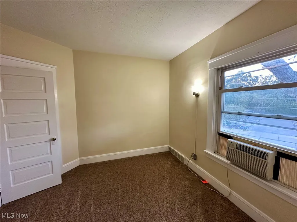 Empty room with dark carpet and a textured ceiling