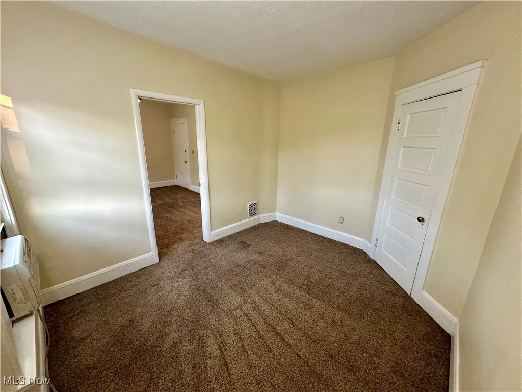 Unfurnished room with dark colored carpet and a textured ceiling