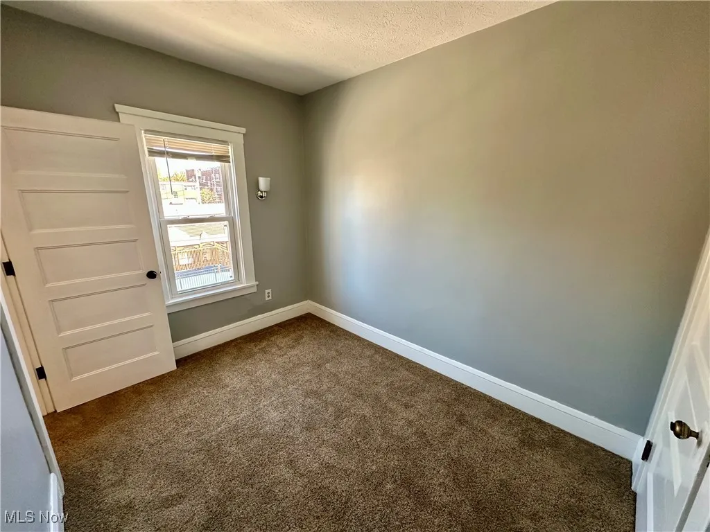 Unfurnished room with dark carpet and a textured ceiling