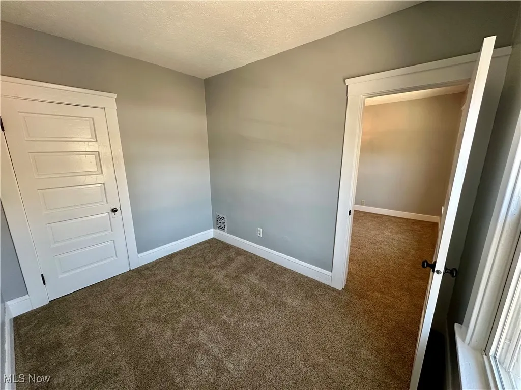Empty room featuring a textured ceiling and dark carpet