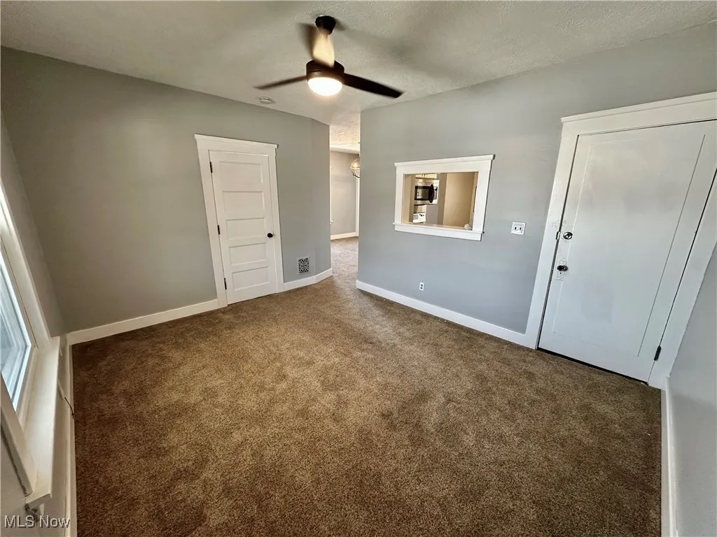 Unfurnished bedroom featuring a textured ceiling, carpet floors, and a ceiling fan