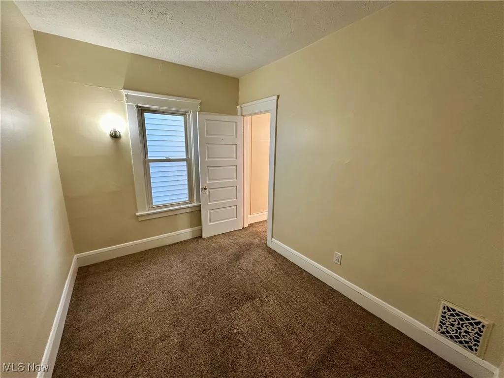 Unfurnished bedroom with dark carpet and a textured ceiling
