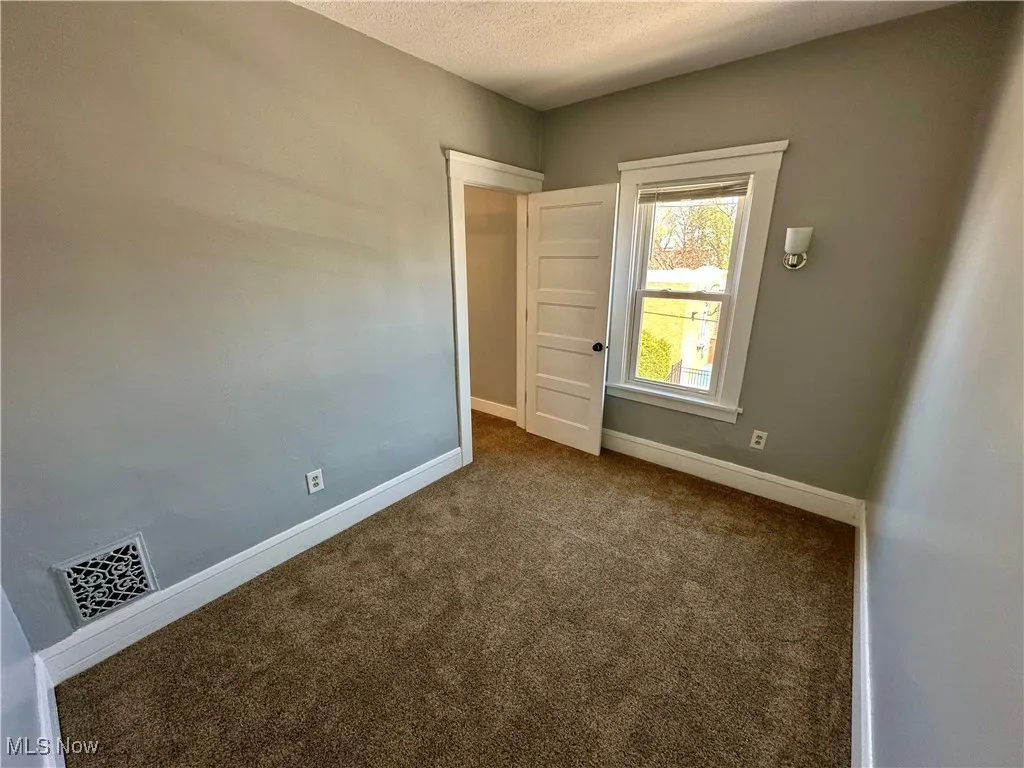 Empty room featuring dark colored carpet and a textured ceiling