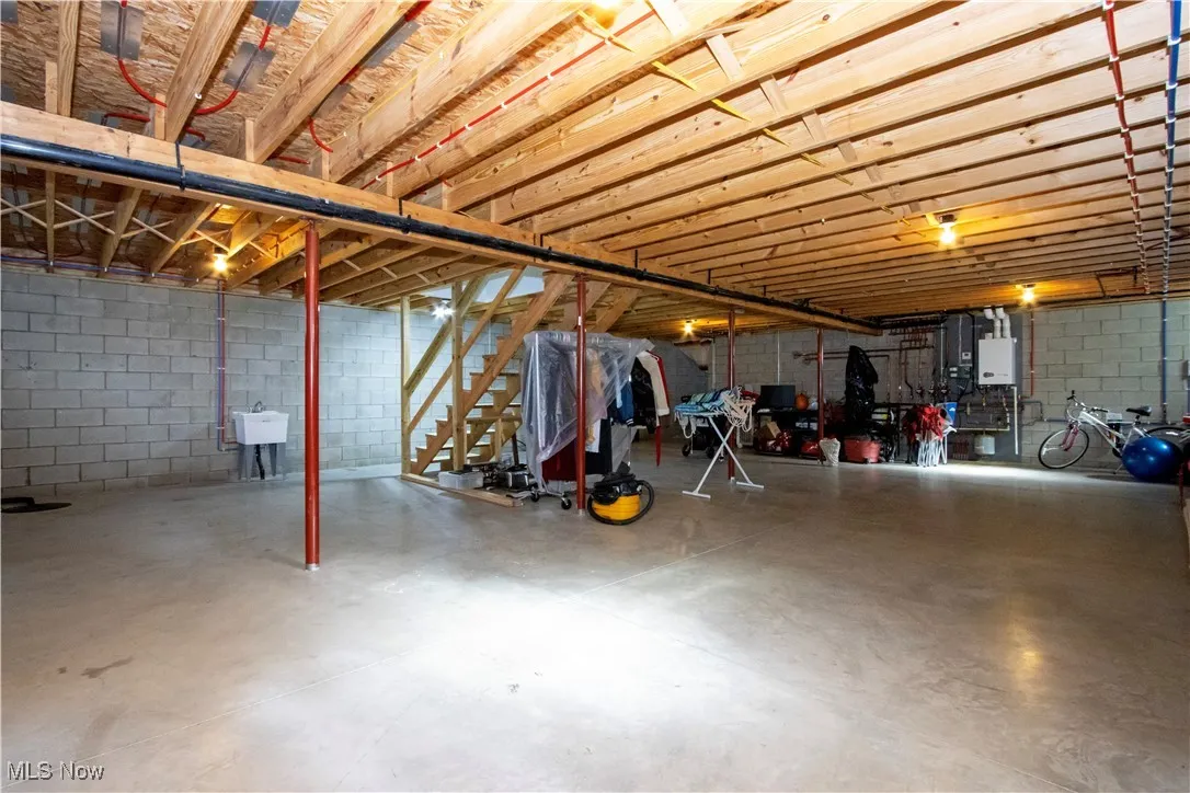 Unfinished basement with concrete block wall and stairs
