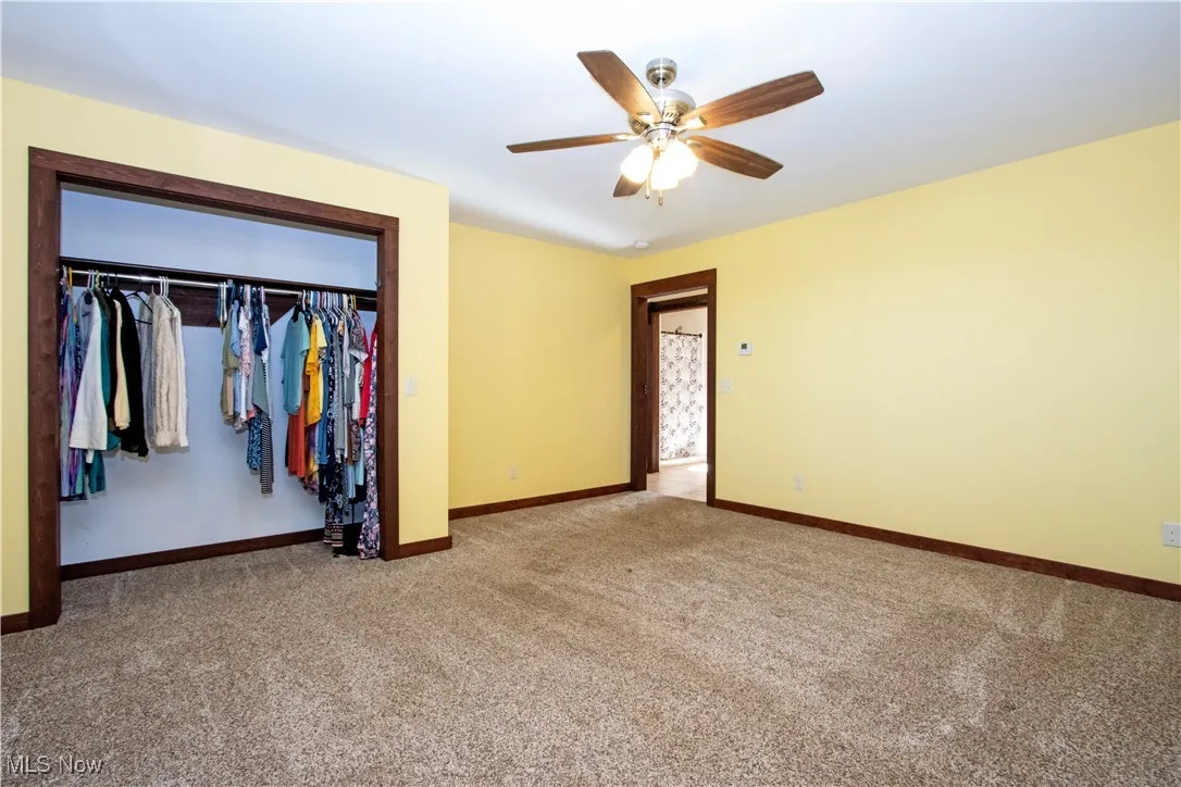 Unfurnished bedroom featuring carpet floors, a closet, and a ceiling fan
