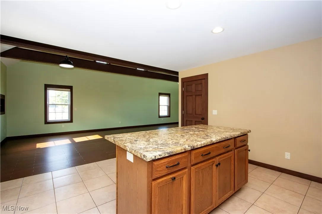 Kitchen featuring brown cabinets, light tile patterned floors, a kitchen island, plenty of natural light, and recessed lighting