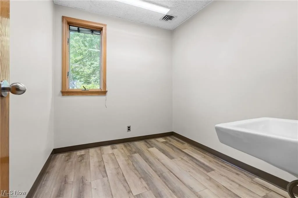 Empty room featuring light wood finished floors and a textured ceiling