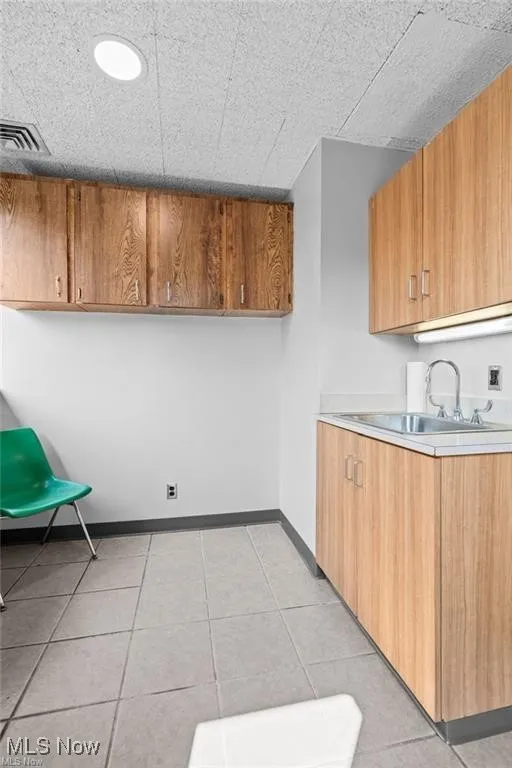 Kitchen with light countertops, light tile patterned flooring, and brown cabinets
