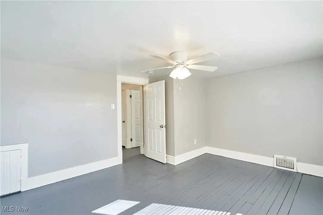 Empty room with dark wood-style floors and a ceiling fan