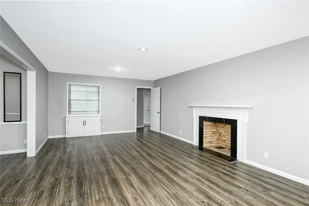 Unfurnished living room with dark wood-type flooring, a tile fireplace, and recessed lighting
