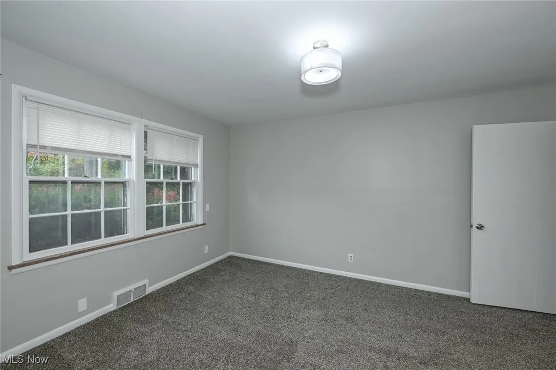 Spare room featuring carpet flooring and baseboards