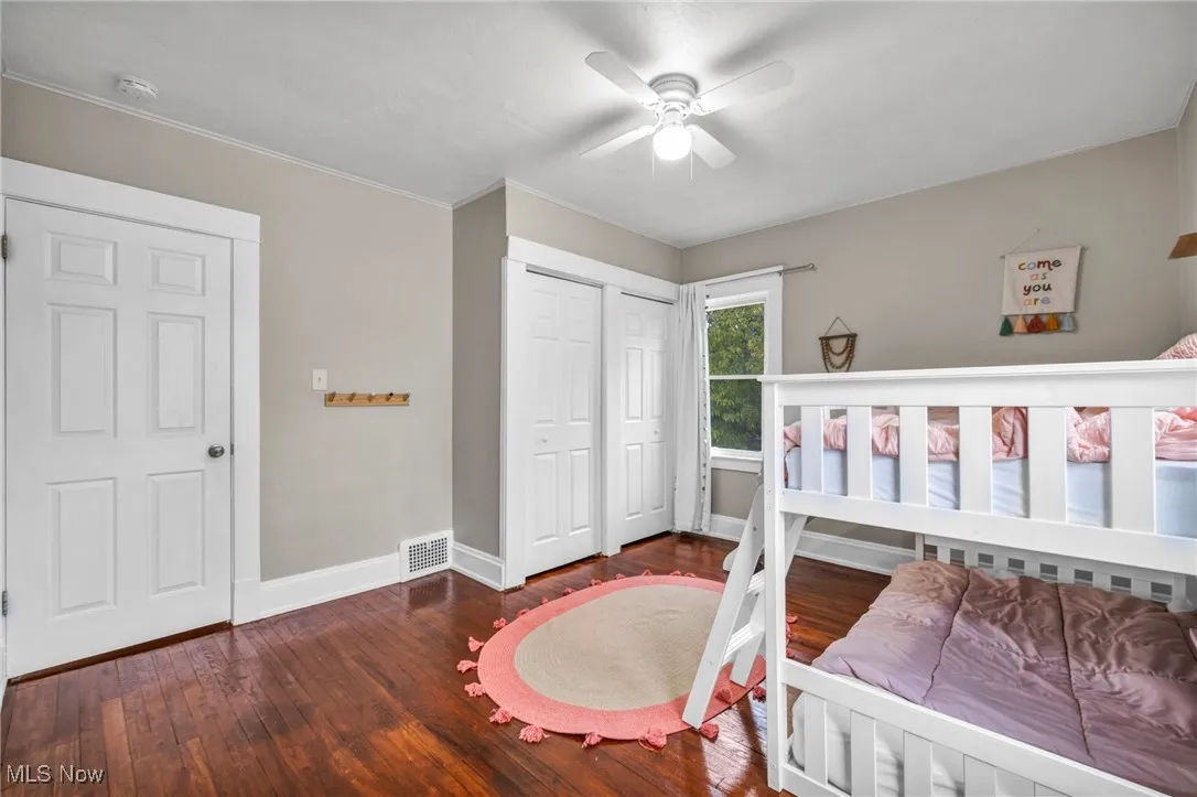 Bedroom with dark wood-style flooring, two closets, and ceiling fan