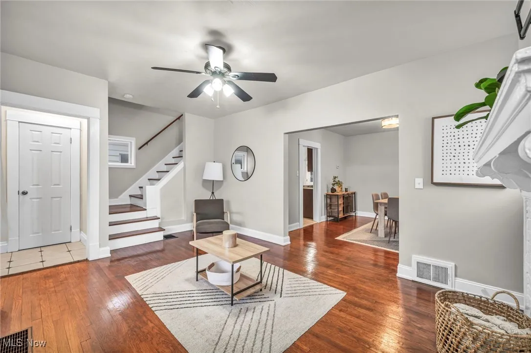Living room featuring stairs, dark wood-type flooring, and a ceiling fan