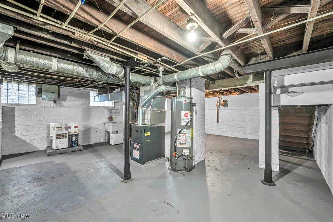 Below grade area with water heater, heating unit, electric panel, and stairway