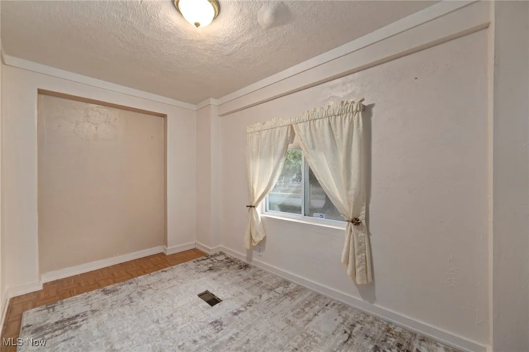 Spare room featuring a textured ceiling and ornamental molding