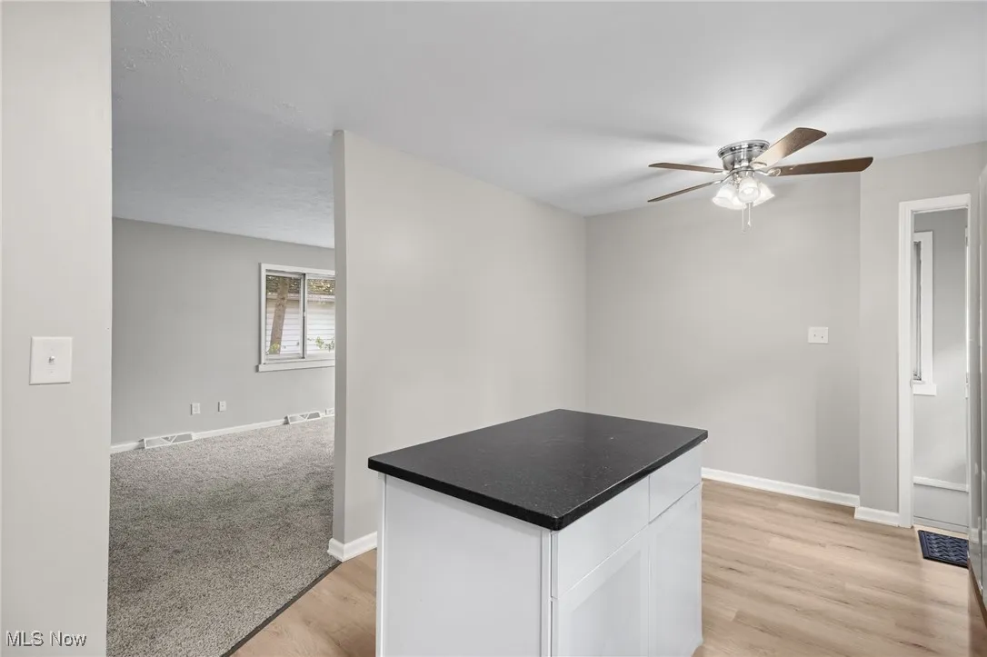 Kitchen featuring white cabinetry, a center island, ceiling fan, and light wood-style flooring