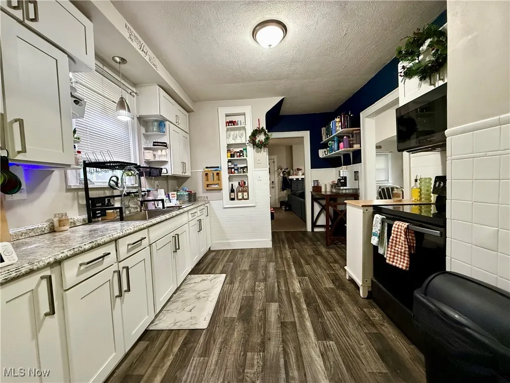 Kitchen with black appliances, white cabinets, a textured ceiling, dark wood-style flooring, and open shelves
