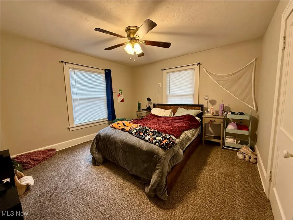 Bedroom featuring carpet, a ceiling fan, and a textured ceiling