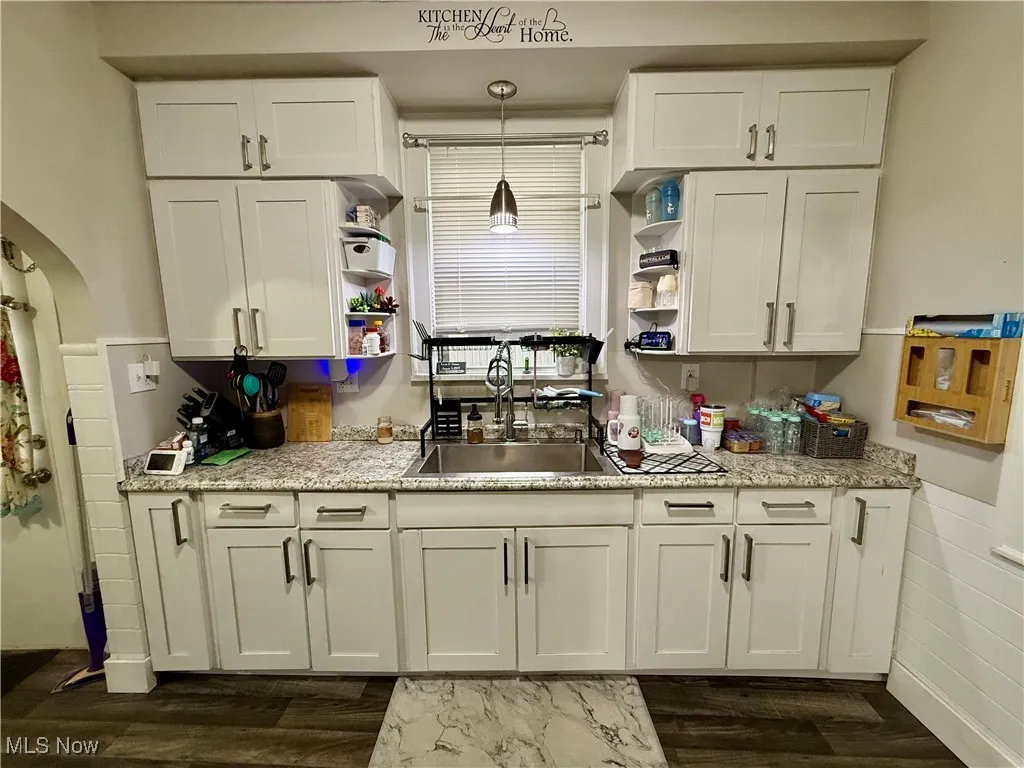 Kitchen featuring open shelves, white cabinetry, dark wood-style floors, pendant lighting, and arched walkways