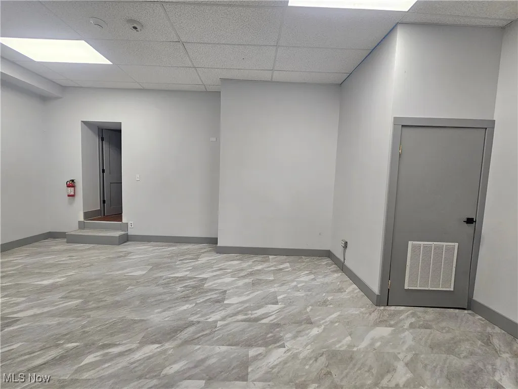 Empty room with baseboards and a drop ceiling