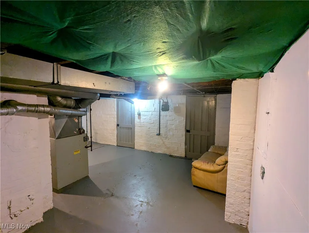 Unfinished basement featuring heating unit and additional storage rooms