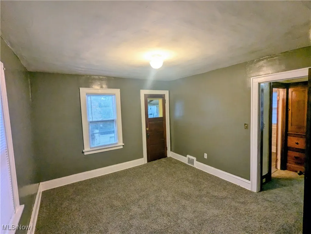Carpeted second floor bedroom with door to enclosed porch
