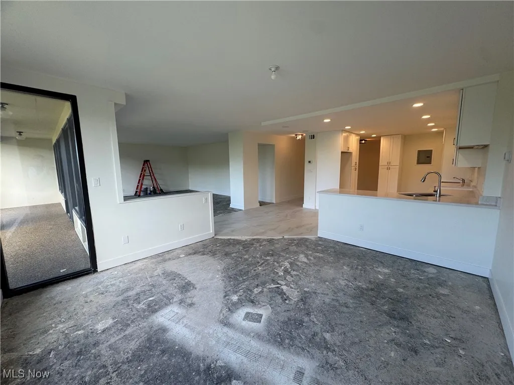 Unfurnished living room featuring baseboards and recessed lighting
