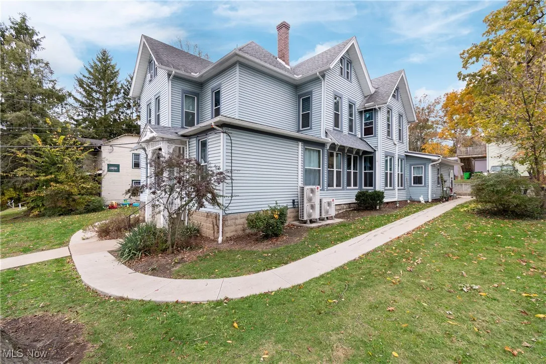 View of side of home featuring a yard, a chimney, and roof with shingles