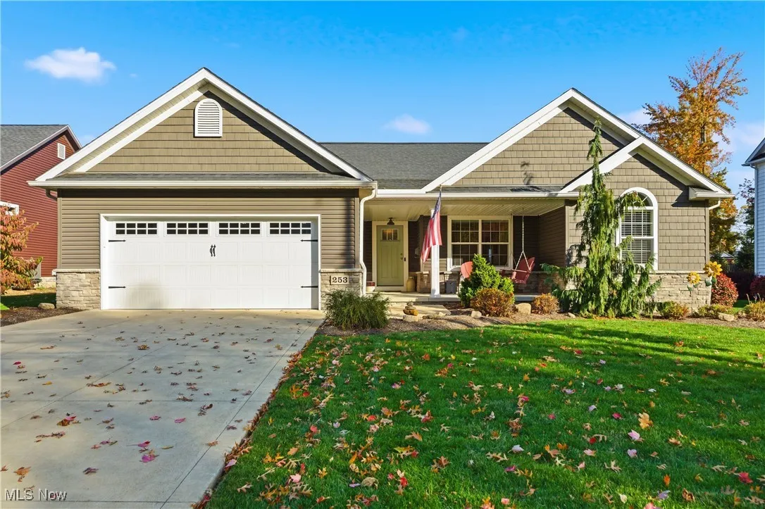 Craftsman-style house with stone siding, a porch, driveway, a front yard, and a garage