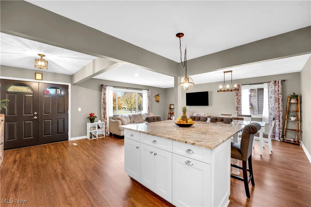 Kitchen with open floor plan, light stone countertops, and dark wood-style flooring