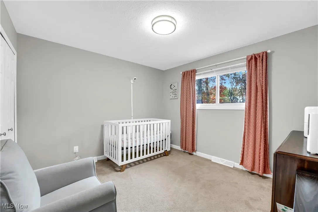 Bedroom with carpet, a crib, and a textured ceiling