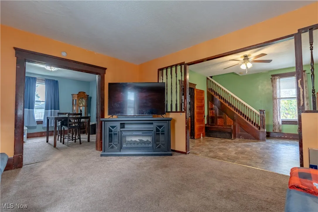 Carpeted living area with plenty of natural light and ceiling fan