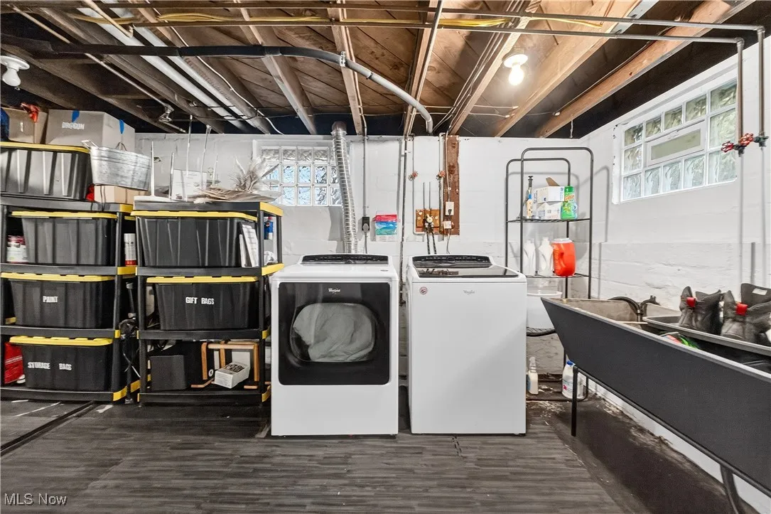 Washroom with healthy amount of natural light, washing machine and dryer, and dark wood finished floors