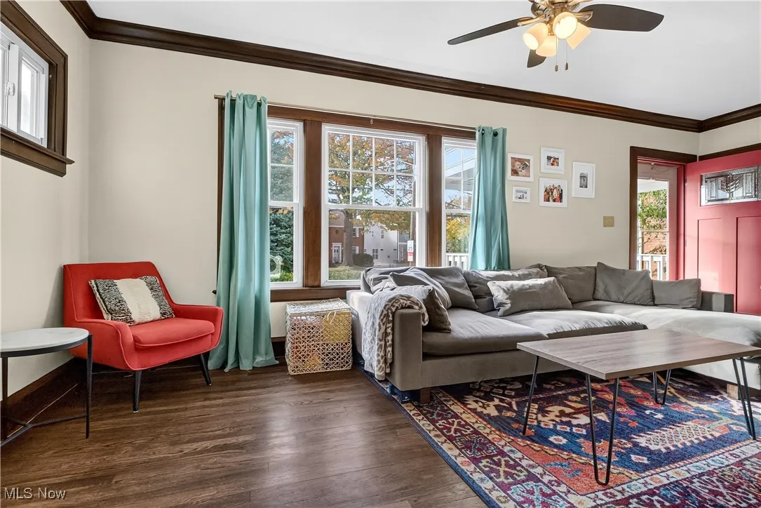 Living room featuring ornamental molding, plenty of natural light, dark wood-style floors, and ceiling fan