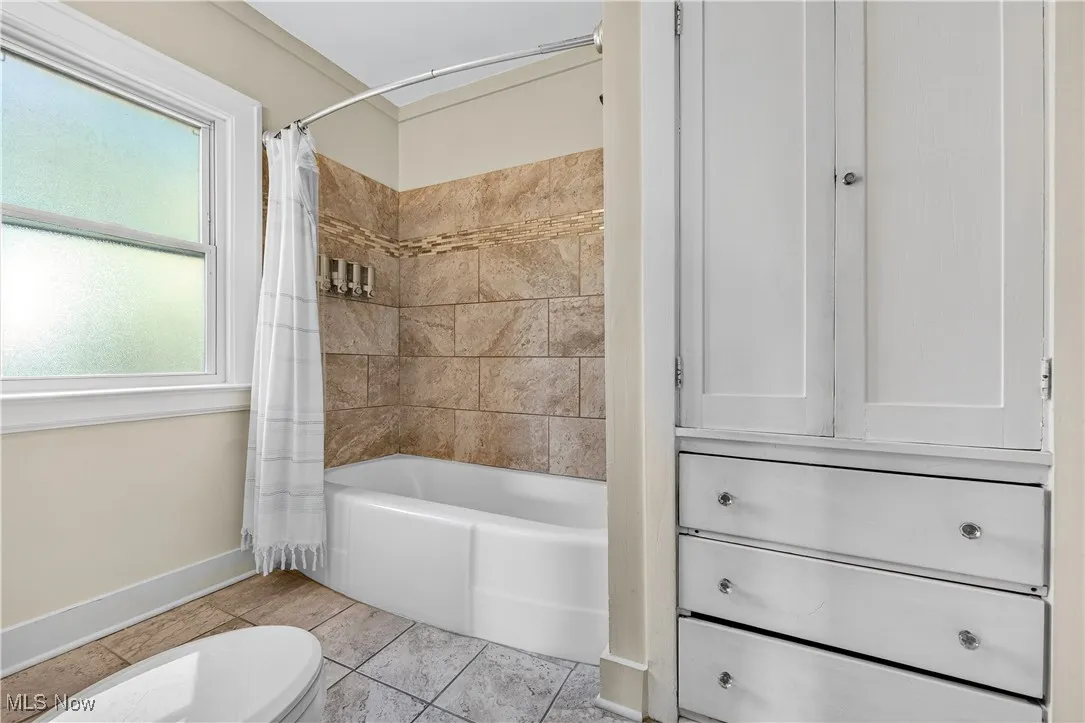 Full bath with shower / bath combination with curtain and light tile patterned flooring
