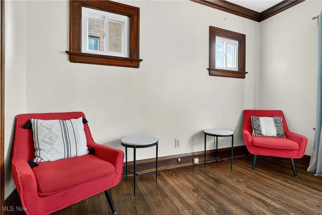 Sitting room with dark wood-style floors and crown molding
